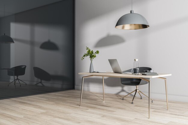 Stylish work place at home with laptop and glass bottle on wooden table parquet and black glossy wall