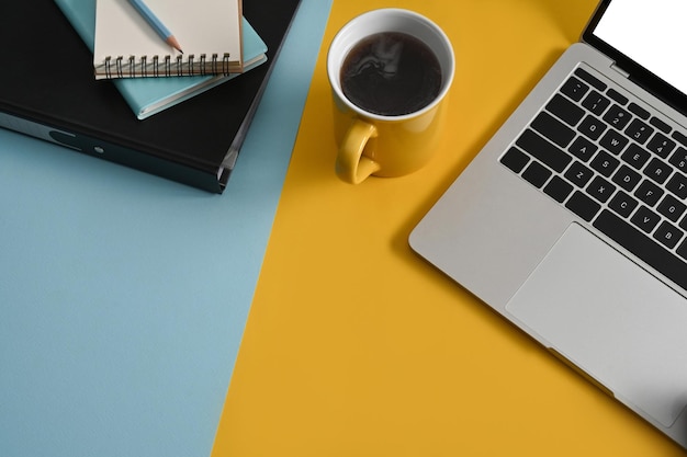 Stylish workplace with computer laptop coffee cup and notepad on colorful background Top view