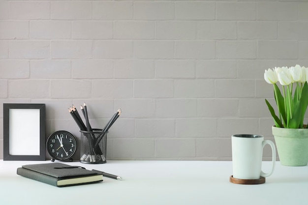 Photo stylish workplace with empty picture frame coffee cup notebook and tulips in a pot copy space for advertise text or information content