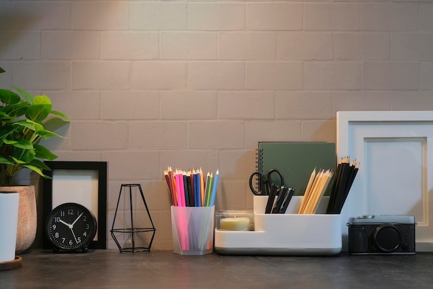 Stylish workplace with stationery picture frame and houseplant on black table