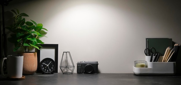 Stylish workplace with stationery picture frame and potted plant on black table Copy space for graphic display montage