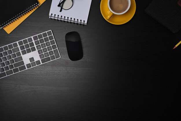 Stylish workspace with coffee cup notebook and keyboard on black table