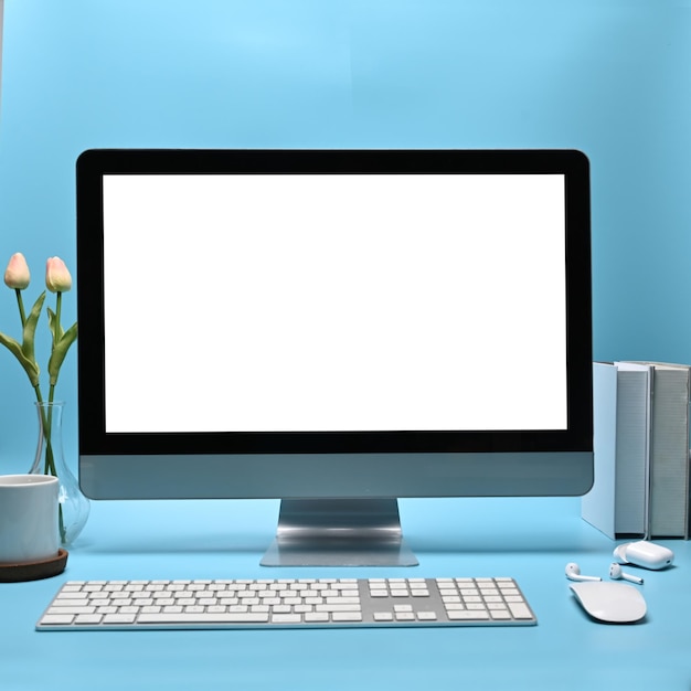 Stylish workspace with computer books and coffee cup on blue background