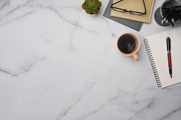 Stylish workspace with cup of coffee notebooks and glasses on marble table Top view