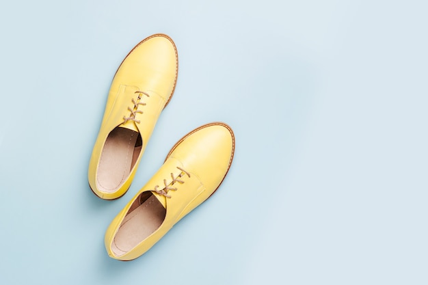 Stylish yellow shoes on pale blue background, flat lay