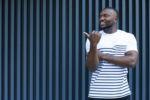 A stylish young AfricanAmerican man poses for the camera by the wall