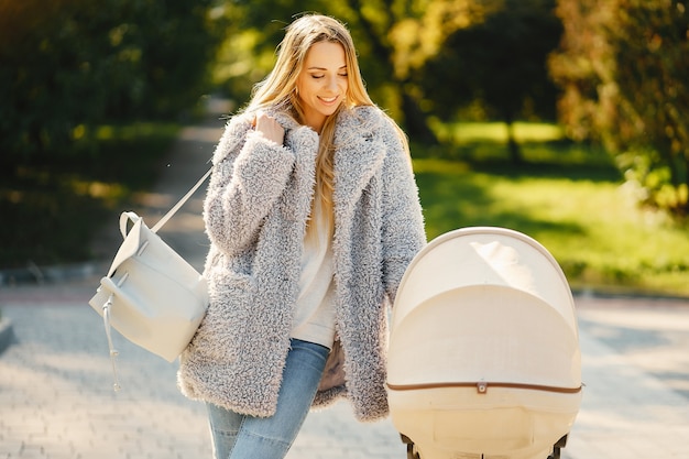 Stylish young blonde mother pushing stroller