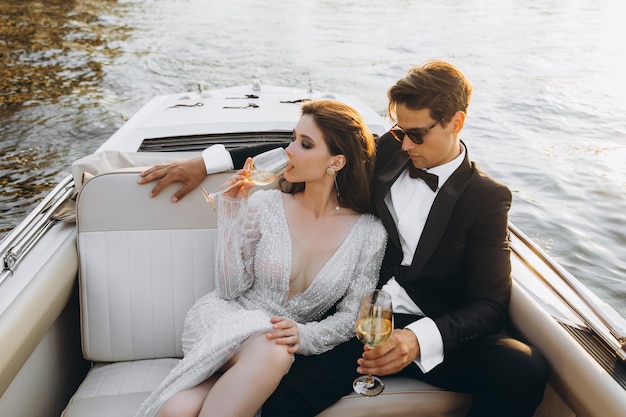 Stylish young bride and groom huging and kissing on yacht