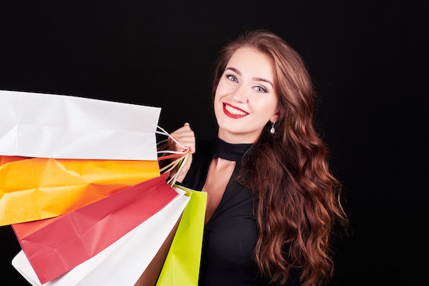 Stylish young brunette woman holding colorful shopping bags
