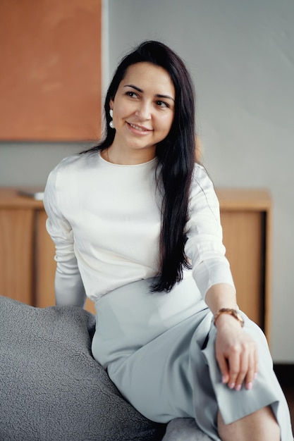 Stylish young brunette woman sitting on a chair in the office Dressed in business clothes waiting