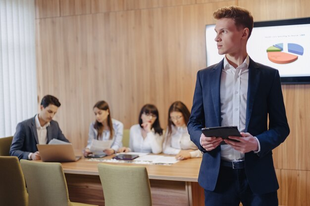 Stylish young businessman wearing a jacket and a shirt working with a tablet