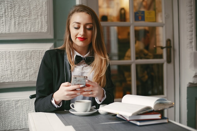 stylish young businesswoman sitting in a cafe with notebook and smartphones