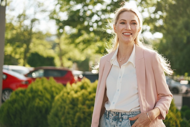 Stylish young businesswoman walking on the city street on sunny day