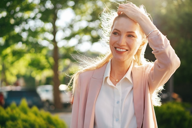 Stylish young businesswoman walking on the city street on sunny day