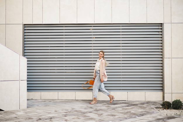 Photo stylish young businesswoman walking on the city street on sunny day