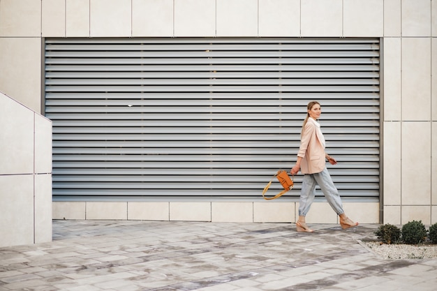 Фото Стильная молодая деловая женщина гуляет по улице города в солнечный день