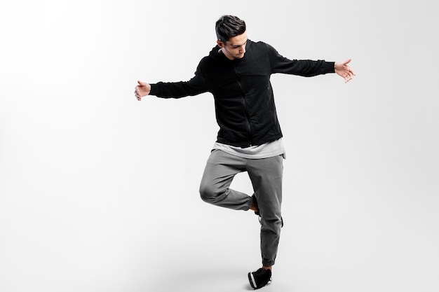 Photo stylish young dancer wearing a black sweatshirt and gray pants is dancing hip-hop