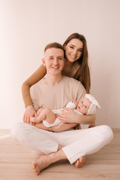 Stylish young family photographed with a little beautiful baby The family expresses love and awe to each other Family and parenting concept