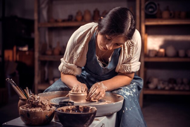 Foto la signorina alla moda mostra il processo di realizzazione di piatti in ceramica utilizzando la vecchia tecnologia. lavoro manuale.