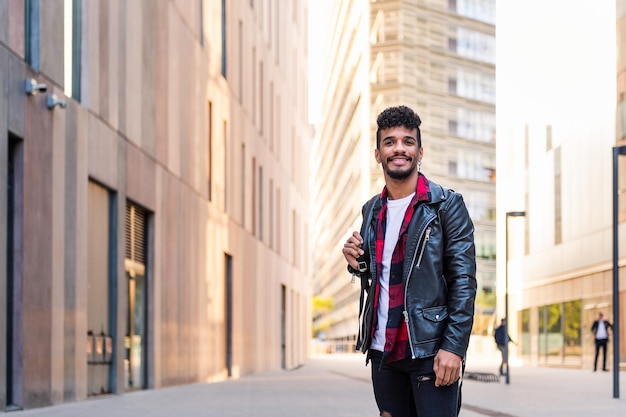 Elegante giovane uomo latino sorridente felice in città, concetto di stile di vita urbano