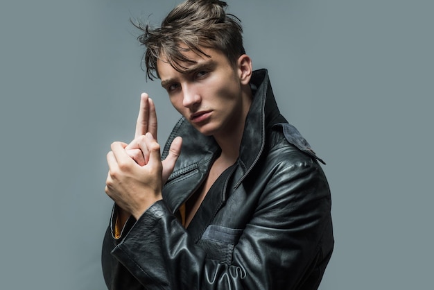 Stylish young man against a grey background with finger gun gesture