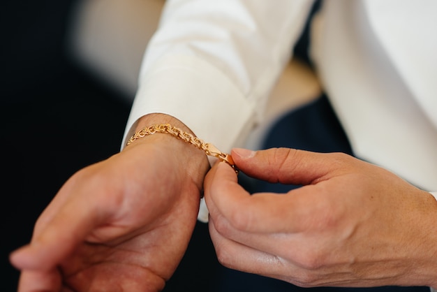 Stylish young man buttoning the cuff links on the sleeves. Style.