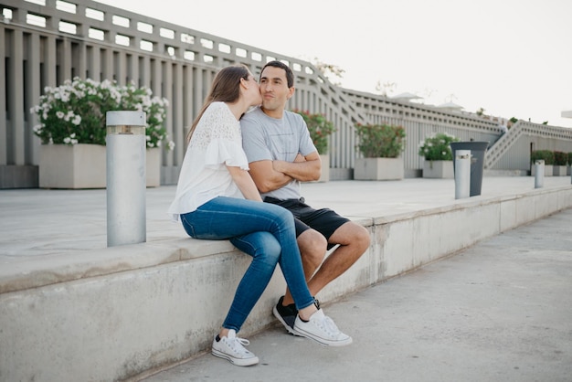 A stylish young man is holding hands with his brunette girlfriend in the port