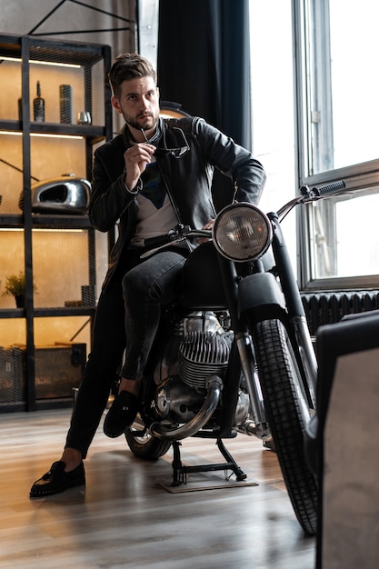 Stylish young man in leather jacket sitting on motorbike.