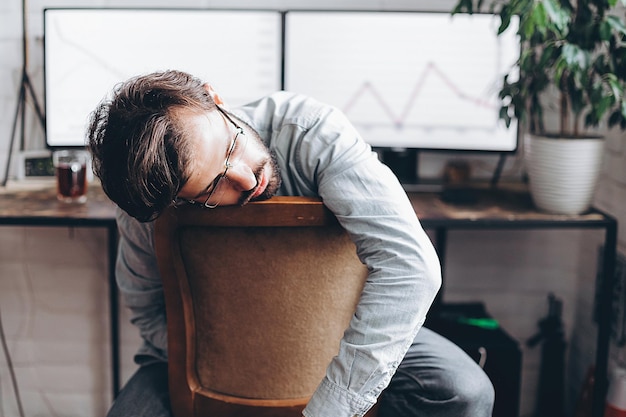 Stylish young man tired of working at the computer at home sitting on a chair