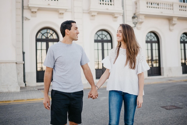 A stylish young man with his brunette girlfriend are strolling through the port in Spain