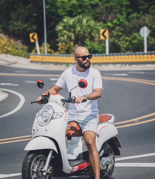 Stylish young man with his motorbike on the road