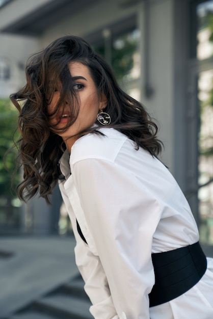 Stylish young model posing near office building.