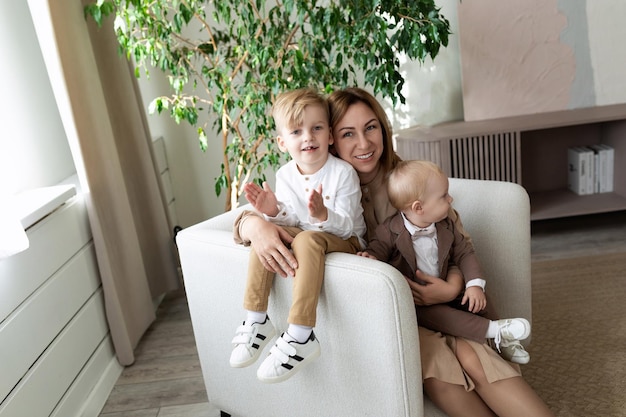 Stylish young mother with two small children looking at the camera with a smile sitting in a chair