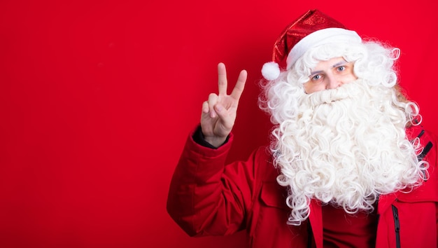 Stylish young Santa in all red shows a hello sign to everyone