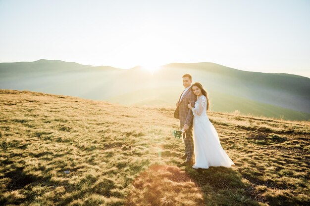 写真 スタイリッシュな若い結婚式のカップルは、美しい山々でポーズをとって楽しんでいます