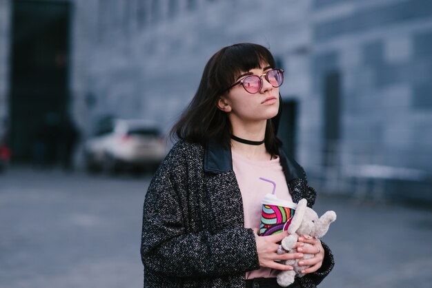 Stylish young woman on the city streets with a paper cup