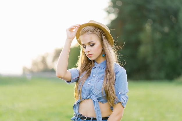 Stylish young woman in a hat walks outdoors in summer