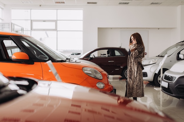 A stylish young woman is choosing a new car in a car store