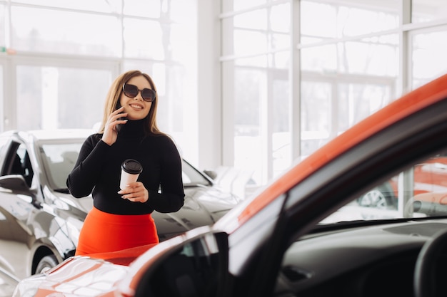 Photo a stylish young woman is looking for a new car in a car store