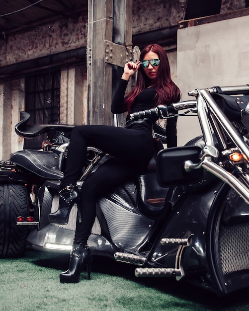 Foto modello alla moda della giovane donna che posa su una mostra del motociclo.