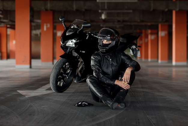 Stylish young woman motorcycle rider with beautiful eyes in black protective gear and fullface