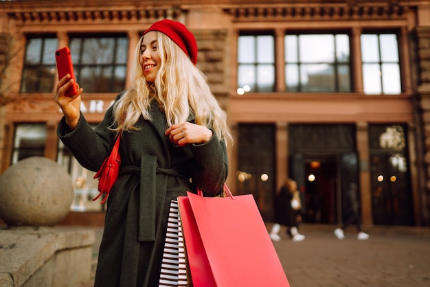 Стильная молодая женщина в модной одежде с сумками для покупок после шоппинга
