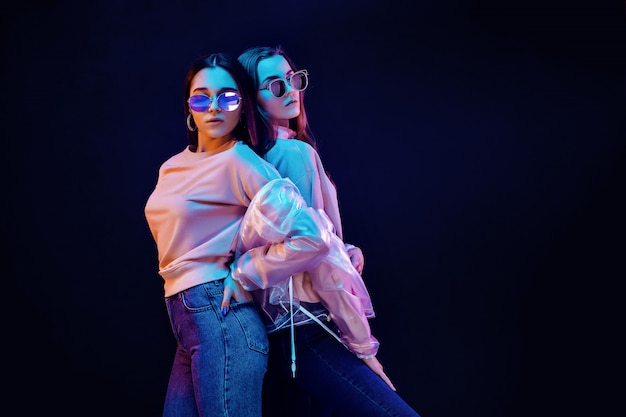 Stylish young women posing in neon light