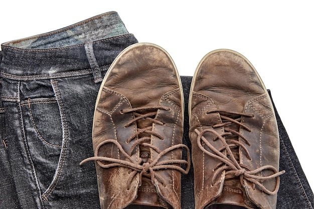 Stylishly distressed vintage brown leather shoes and black jeans isolated on white background