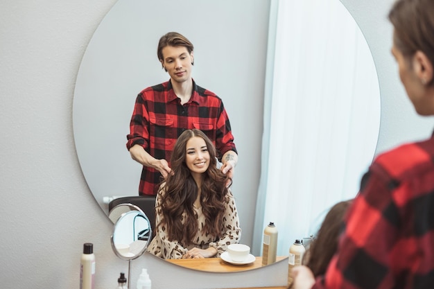 Stylist barber styling long hair for beautiful asian young woman in the beauty salon working moment