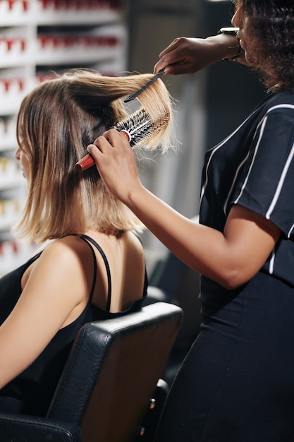 Stylist brushing hair of client