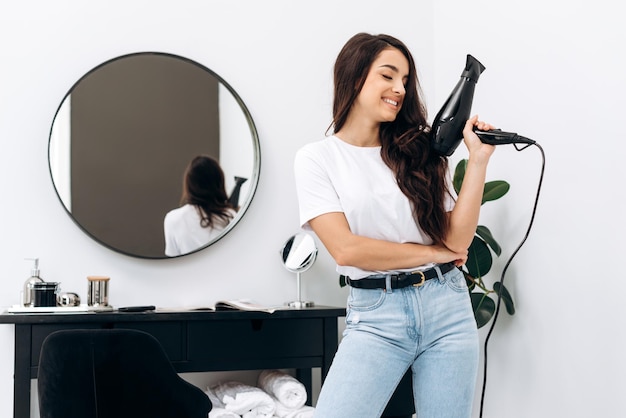 Stylist die een droger vasthoudt terwijl ze in haar studio staat en het drogen van haar voorbereidt voor toekomstige klanten in het schoonheidssalon Haarbehandelingsconcept