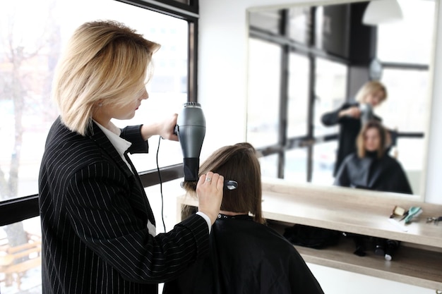 Stylist die vrouwenhaar in salon droogt