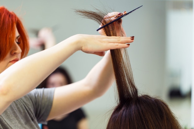 Stylist lijnt het haar van de klant uit met een stijltang