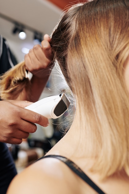 Stilista che fa taglio di capelli con il rasoio elettrico